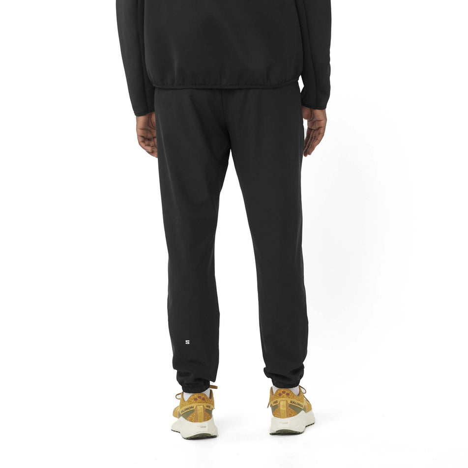 Back view of a model wearing the Salomon Men's SHKout Core Pants in the Deep Black colourway. (8577969291426)