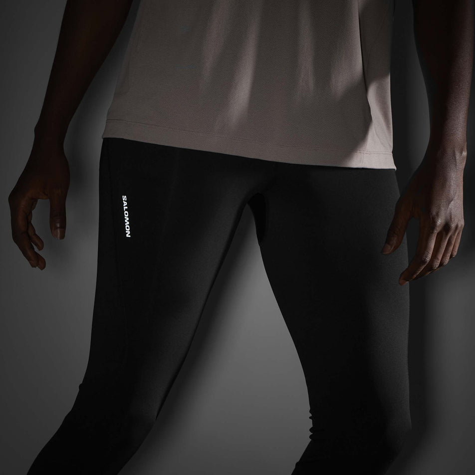 The reflective Salomon logo on the side of the Salomon Men's SHAKEout CORE Tights in theDeep Black colourway. (8736846545058)