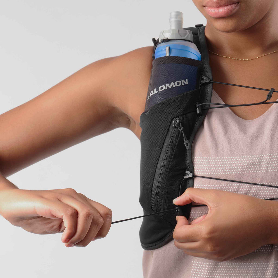 Front view of model demonstrating the secure tightening system on the Salomon Women's ADV Skin 12 Set Running Vest in the Black/Asphalt colourway.