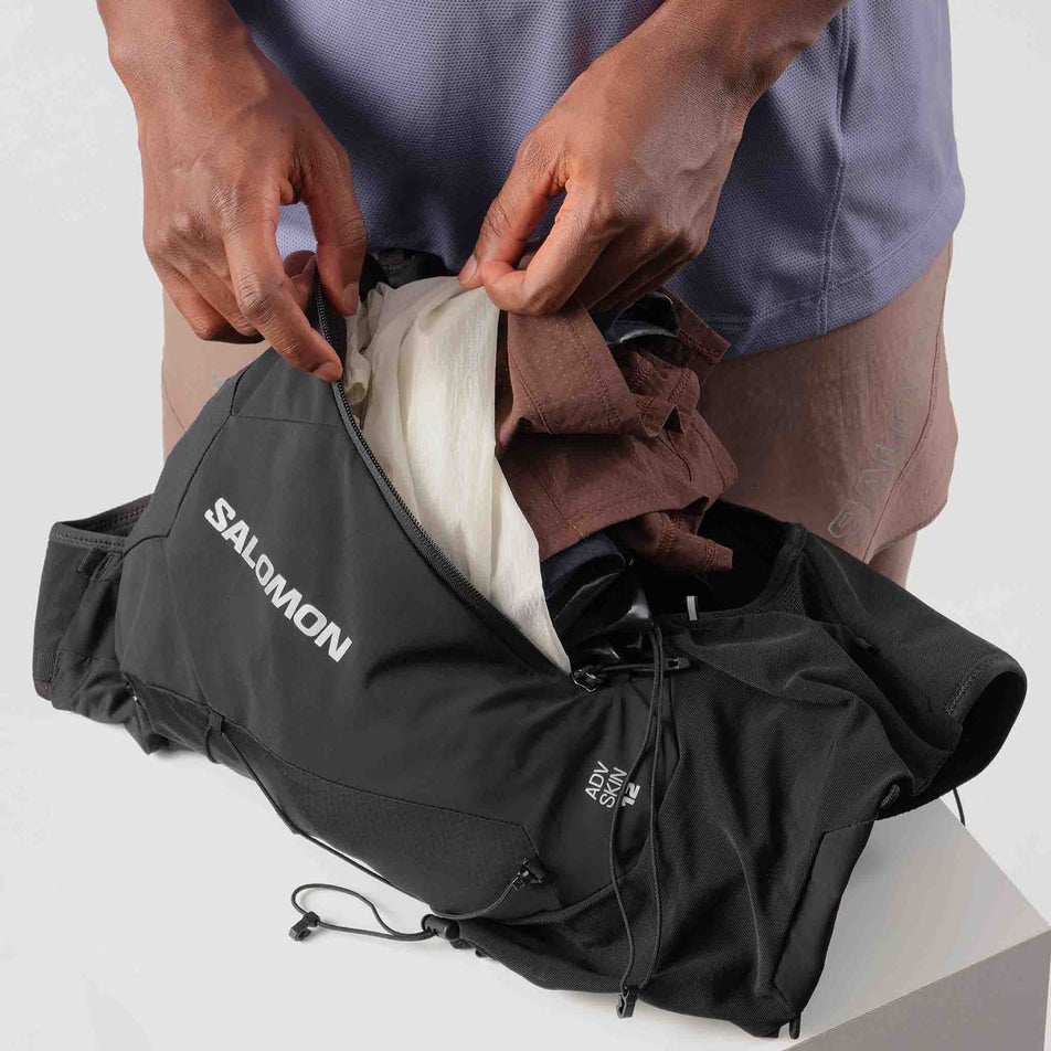 A model packing kit into the Salomon Unisex ADV Skin 12 Running Vest in the Black colourway.