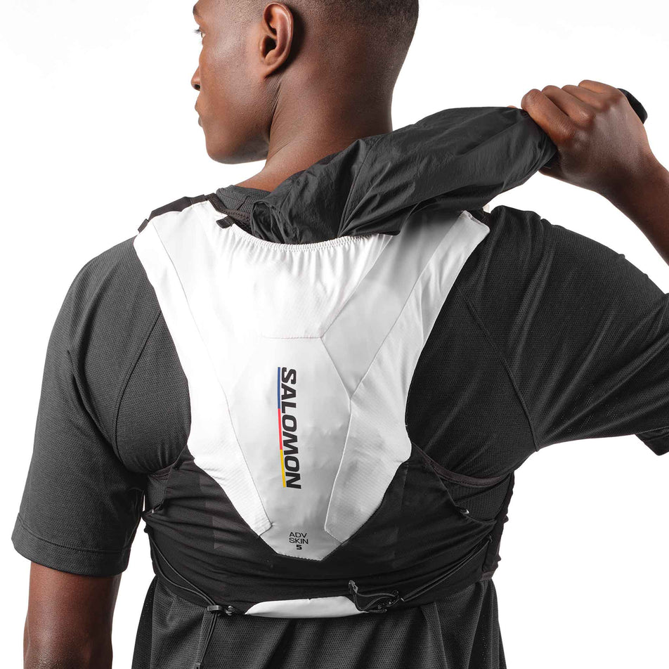 A model demonstrating the storage tunnel on the Salomon Unisex ADV Skin 5 Race Flag Running Vest with flasks included in the Black/White colourway. (8575896682658)