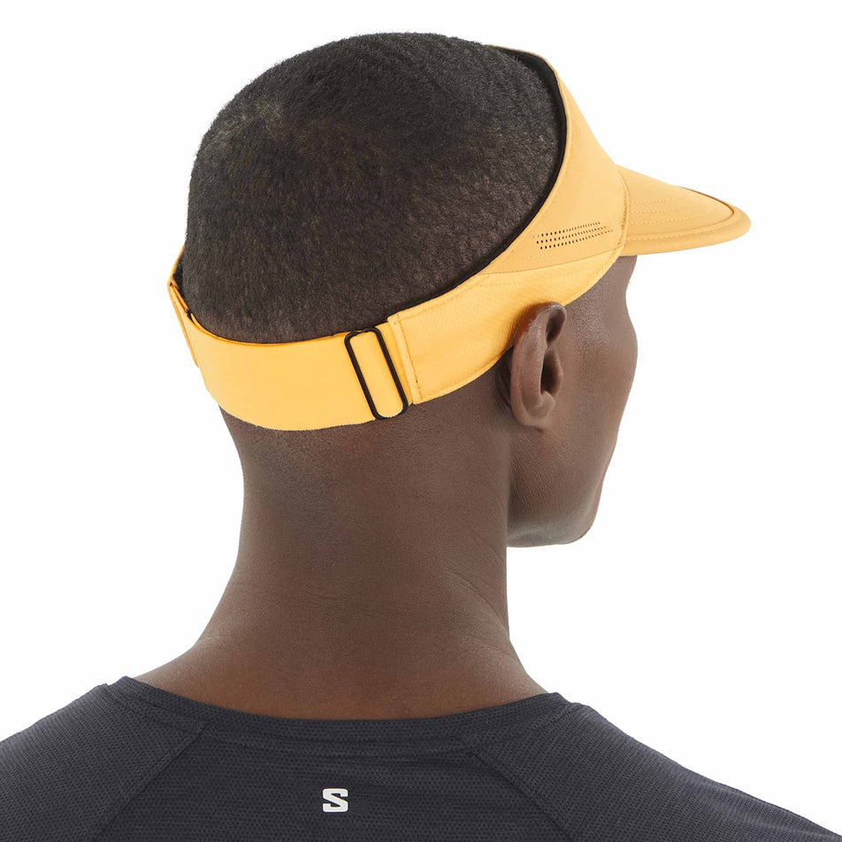 Back view of a model wearing the Salomon Unisex SHKout Visor in the Warm Apricot colourway. (8577889108130)