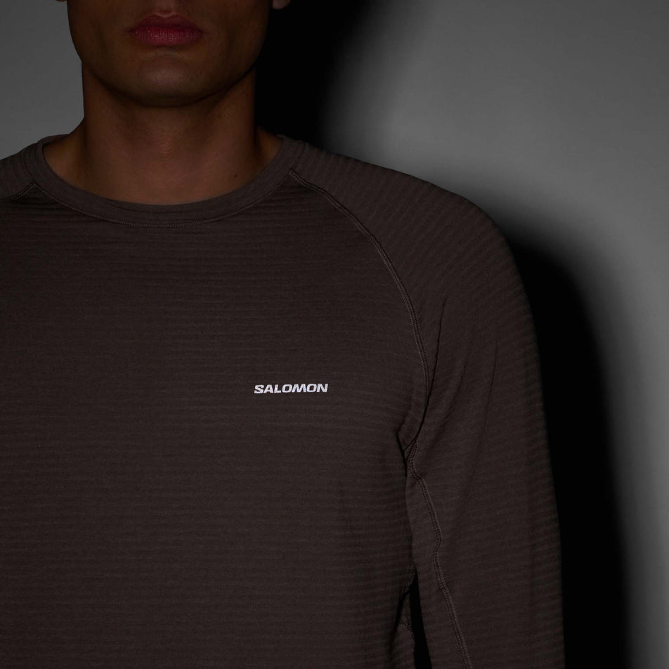 The reflective Salomon logo on the front of the Salomon Men's Essential Lightwarm Crewneck Pullover in the Iron colourway. (8736775143586)