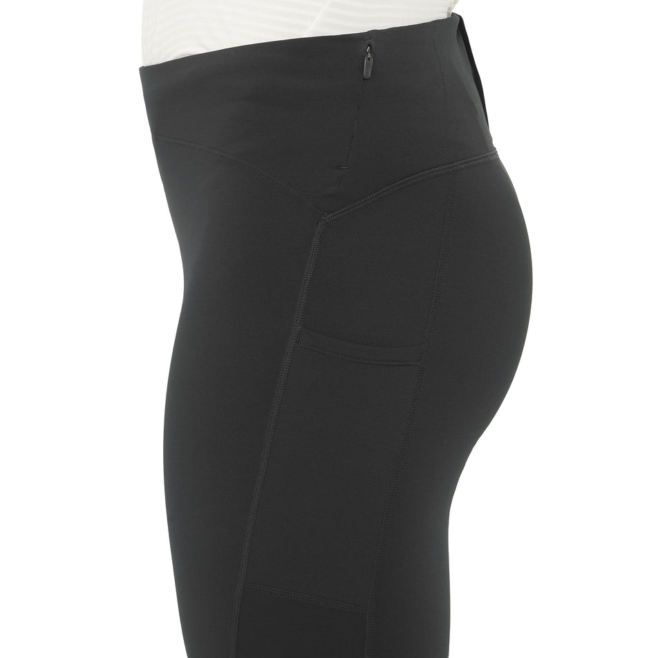 Side view of a model wearing the Salomon Women's SHAKEout Core Warm Tights in the Deep Black colourway. (8781930561698)
