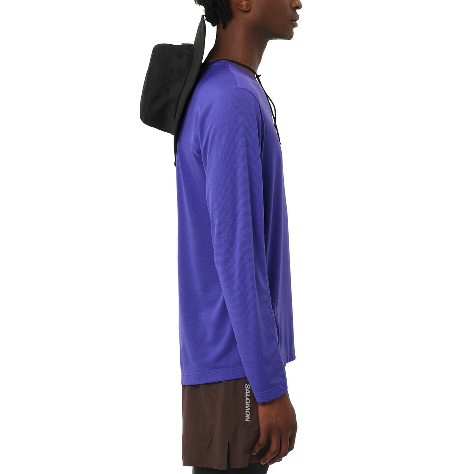 Side view of a model wearing the Salomon Men's SHAKEout CORE Long-Sleeve T-Shirt in the Liberty colourway. (8736829866146)
