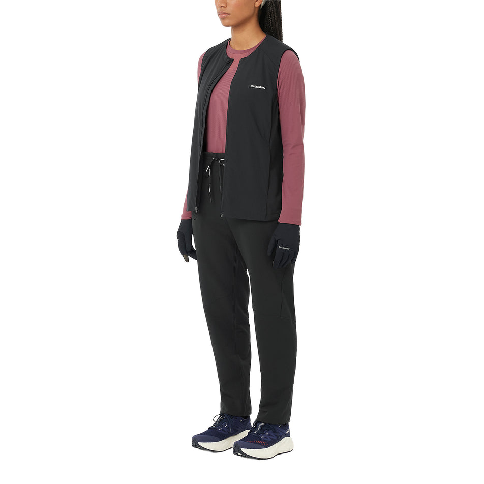 Angled view of a model wearing the Salomon Women's SHAKEout HexaFlow Pants in the Deep Black colourway. (8781921091746)