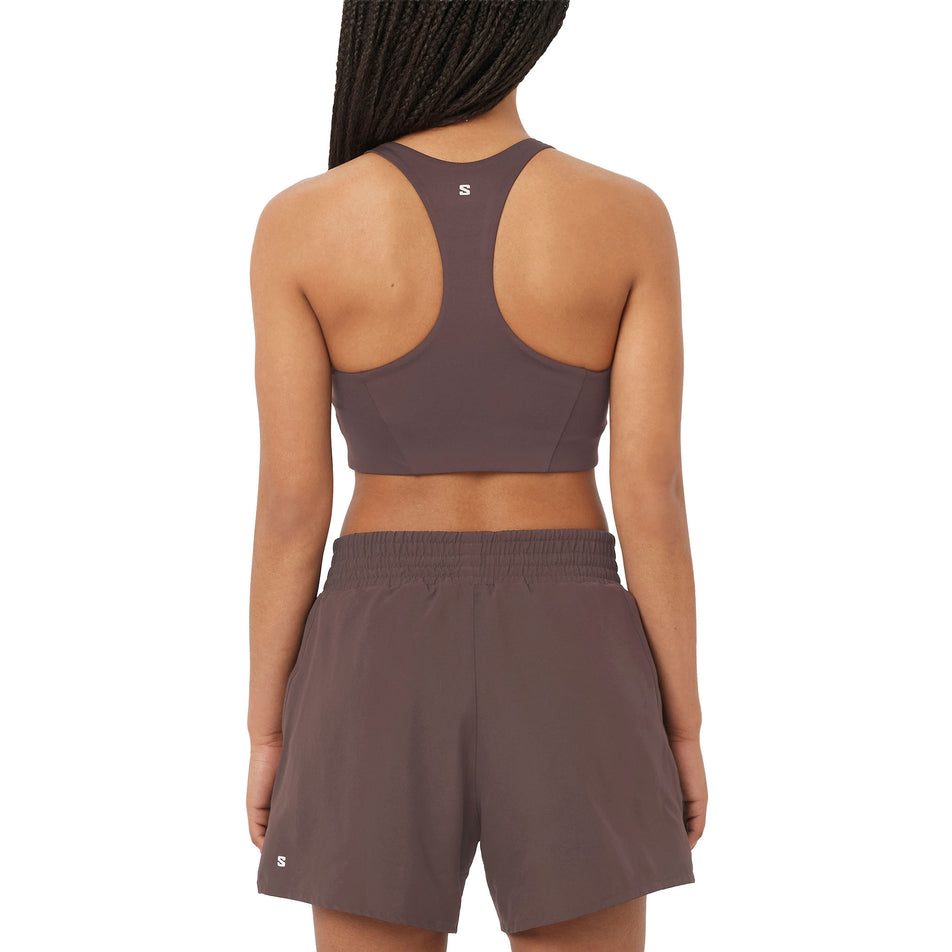 Back view of a model wearing the Salomon Women's SHKout CORE Sports Bra in the Coffee Bean colourway. (8727006281890)