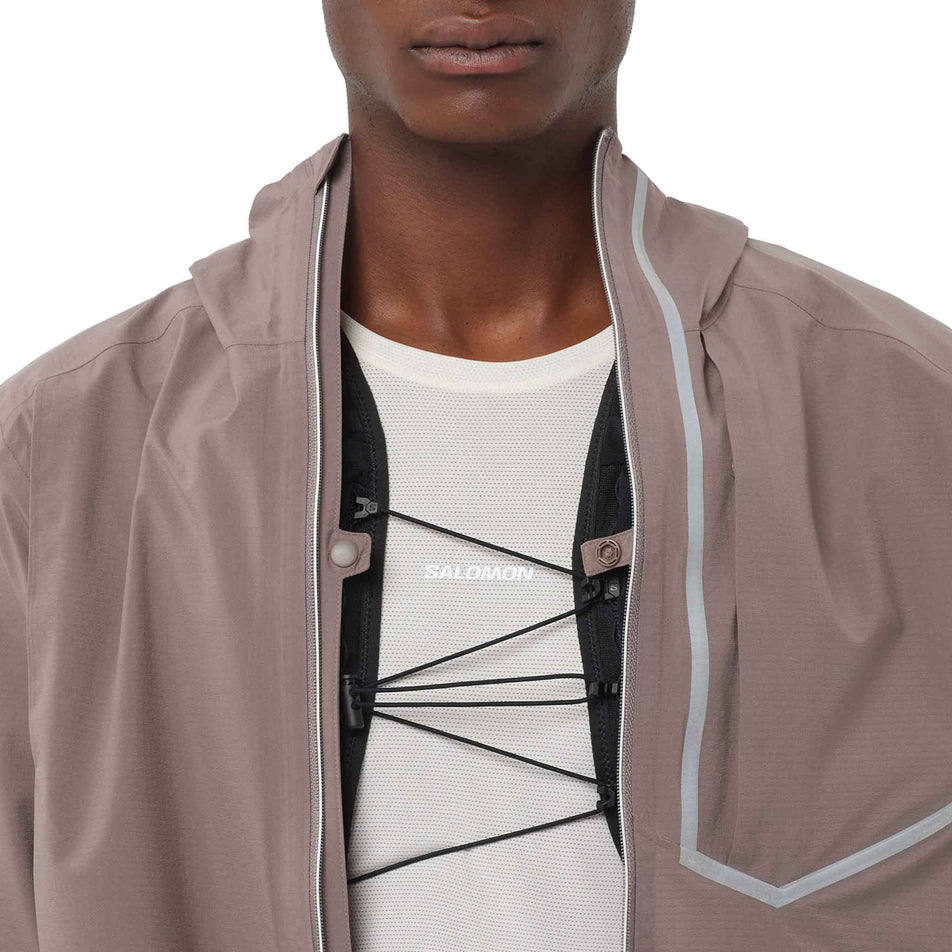 A model demonstrating a hydration vest being worn under the Salomon Men's Bonatti Trail Shell Jacket in the Iron colourway. (8736773374114)