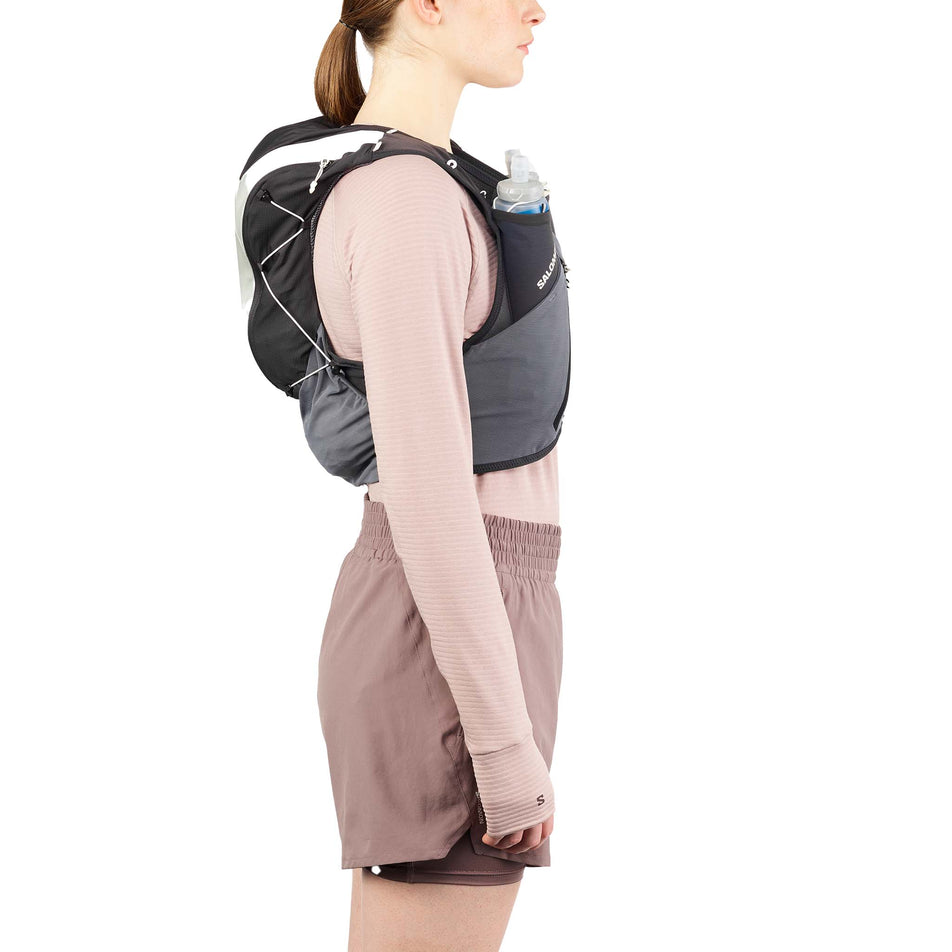 Side view of a model wearing the Salomon Unisex ADV Skin 12 Gradient Running Vest with flasks included in the Phantom/Castlerock/Icicle colourway. (8737327317154)