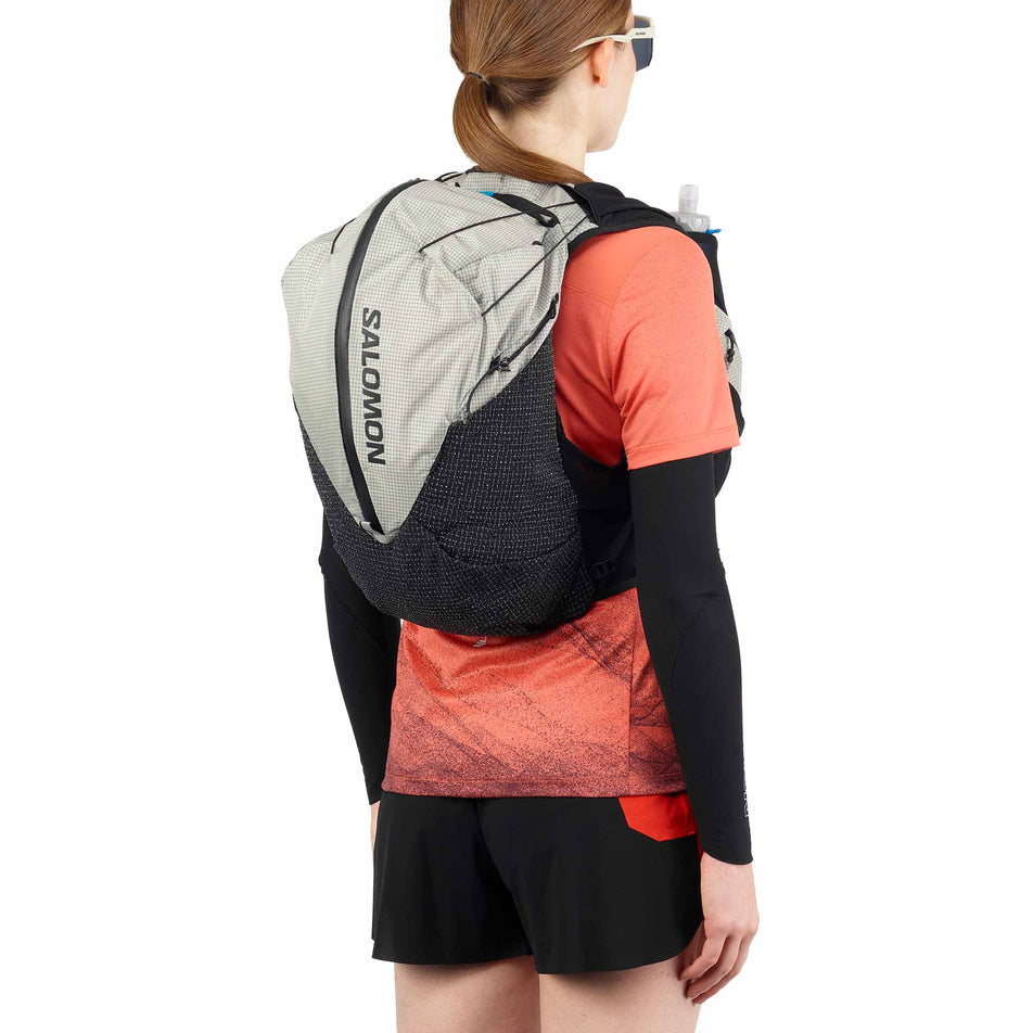 Angled view of a model wearing the Salomon Unisex S/LAB Adventure 20 Running Vest with flasks included in the Black/White colourway. (8737335279778)