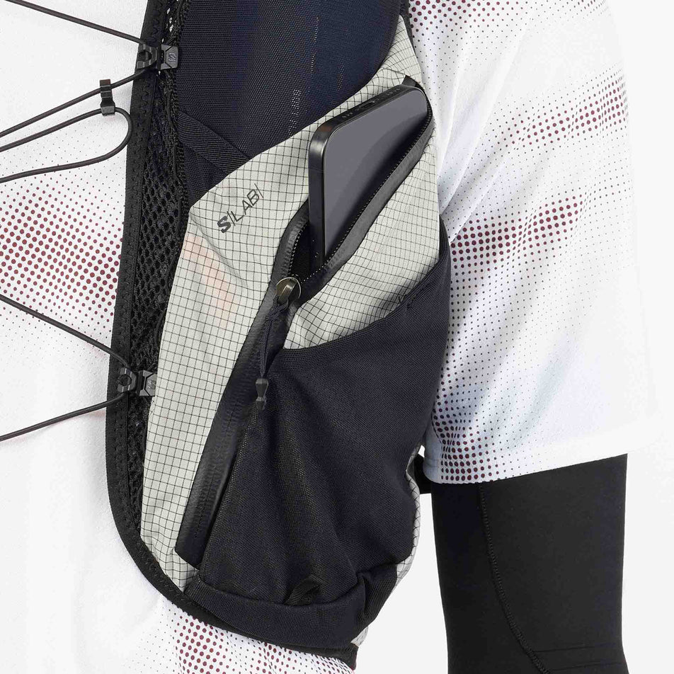 Close-up view of the zipped pocket on the front of the Salomon Unisex S/LAB Adventure 20 Running Vest with flasks included in the Black/White colourway. (8737335279778)