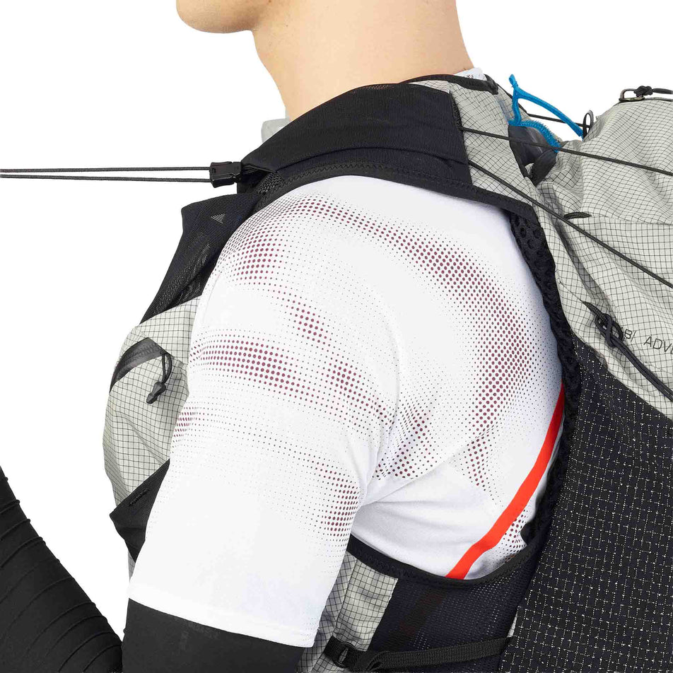 A model demonstrating the tightening cords on the Salomon Unisex S/LAB Adventure 20 Running Vest with flasks included in the Black/White colourway. (8737335279778)