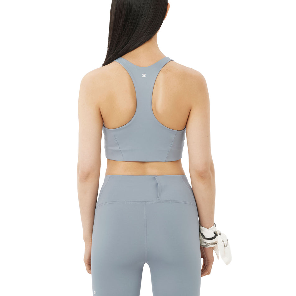 Back view of a model wearing the Salomon Women's SHKout CORE Sports Bra in the Trade Winds colourway.