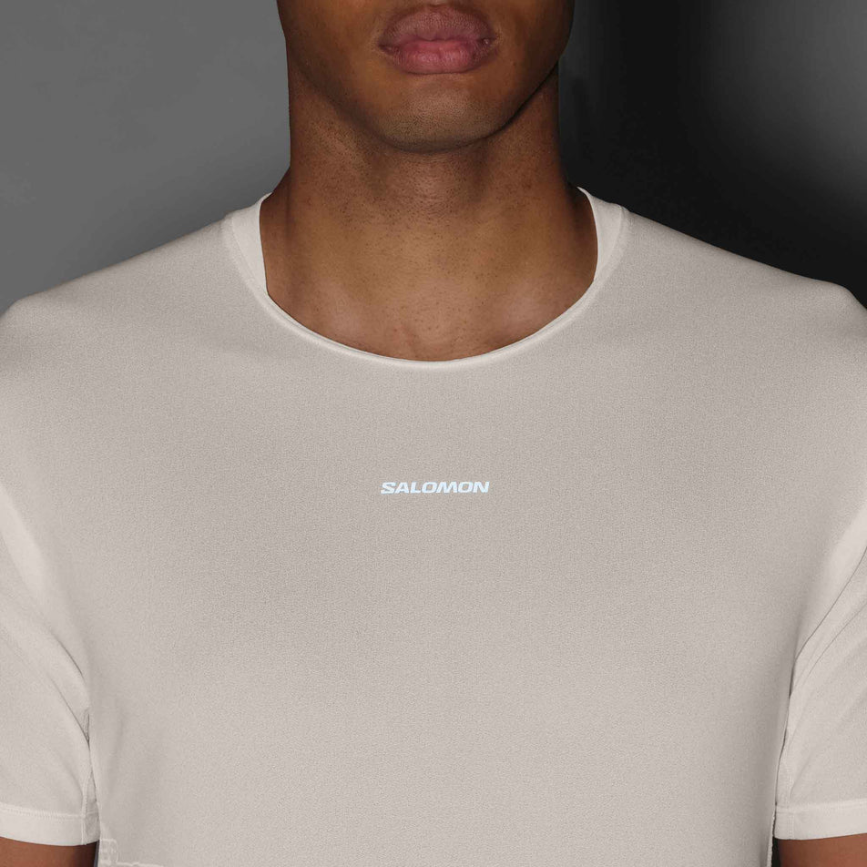 The reflective logo on the front of the Salomon Men's Sense Aero SS Tee GFX in the Whisper White/Raind Day/Bright White colourway.