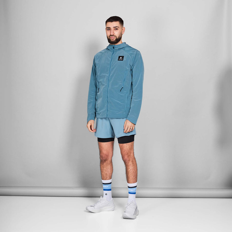 Front view of a model wearing the SAYSKY Men's Clean Pace Shield Jacket in the Blue colourway. Model is also wearing shoes, socks and shorts. (8601240633506)