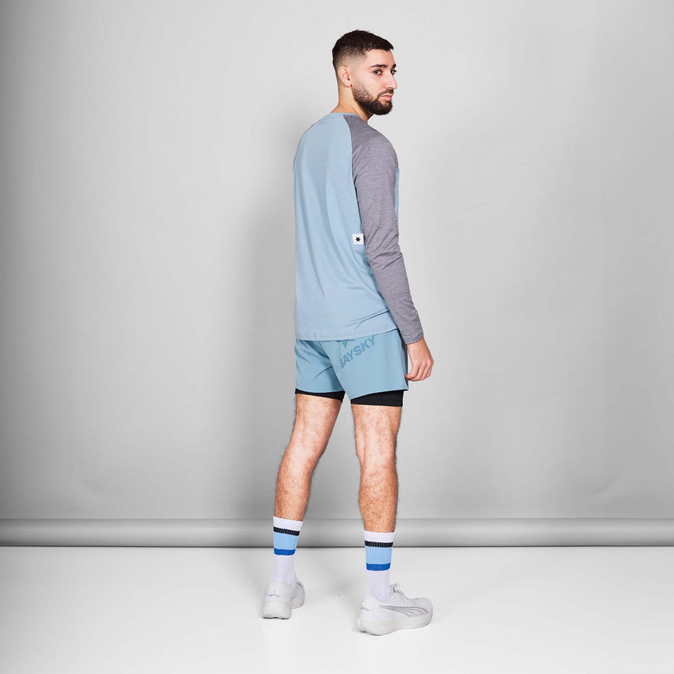 Back view of a model wearing the SAYSKY Men's Logo Pace Long Sleeve in the Blue Melange colourway. Model is also wearing shoes, socks and shorts. (8601261670562)