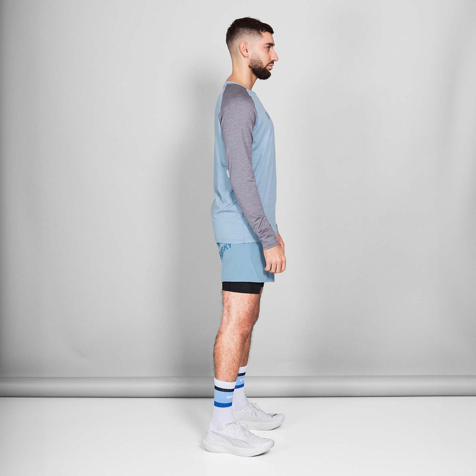 Side view of a model wearing the SAYSKY Men's Logo Pace Long Sleeve in the Blue Melange colourway. Model is also wearing shoes, socks and shorts. (8601261670562)