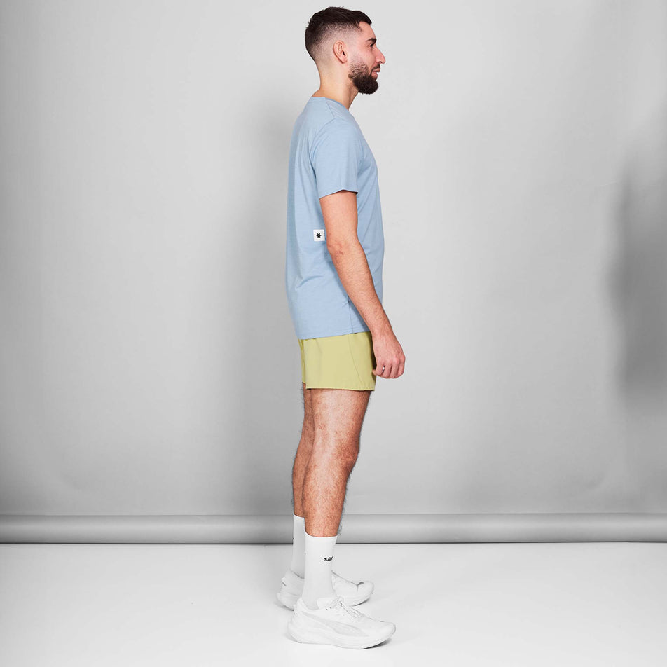 Side view of a model wearing the SAYSKY Men's Logo Pace T-Shirt in the Blue Melange colourway. Model is also wearing shoes, socks and shorts. (8601301647522)