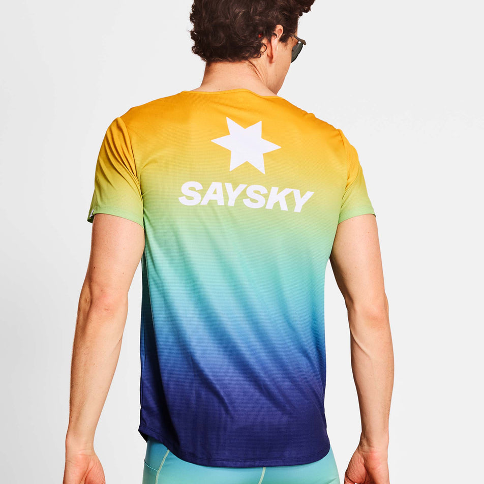 Back view of a model wearing a SAYSKY Men's Drip Dye Flow T-Shirt in the Blue AOP colourway. Model is also wearing legwear and sunglasses. (8675467428002)