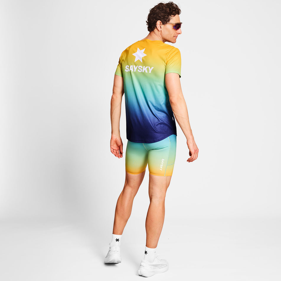 Back view of a model wearing a SAYSKY Men's Drip Dye Flow T-Shirt in the Blue AOP colourway. Model is also wearing sunglasses, legwear, socks and shoes. (8675467428002)