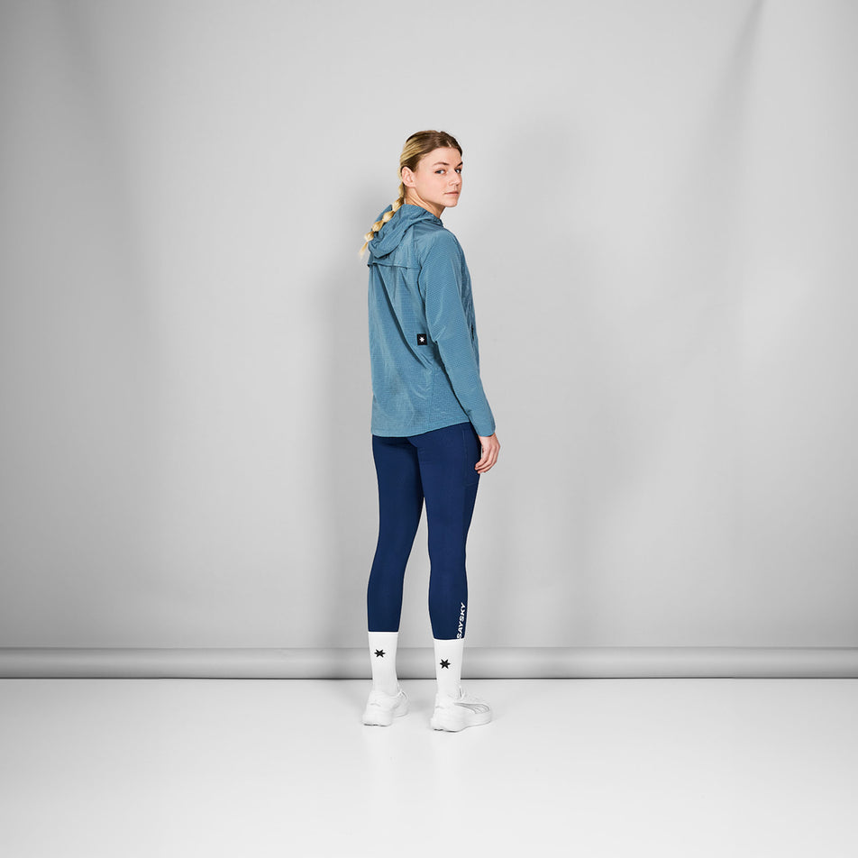 Back view of a model wearing the SAYSKY Women's Clean Pace Shield Jacket in the Blue colourway. Model is also wearing tights, socks and shoes. (8601993445538)