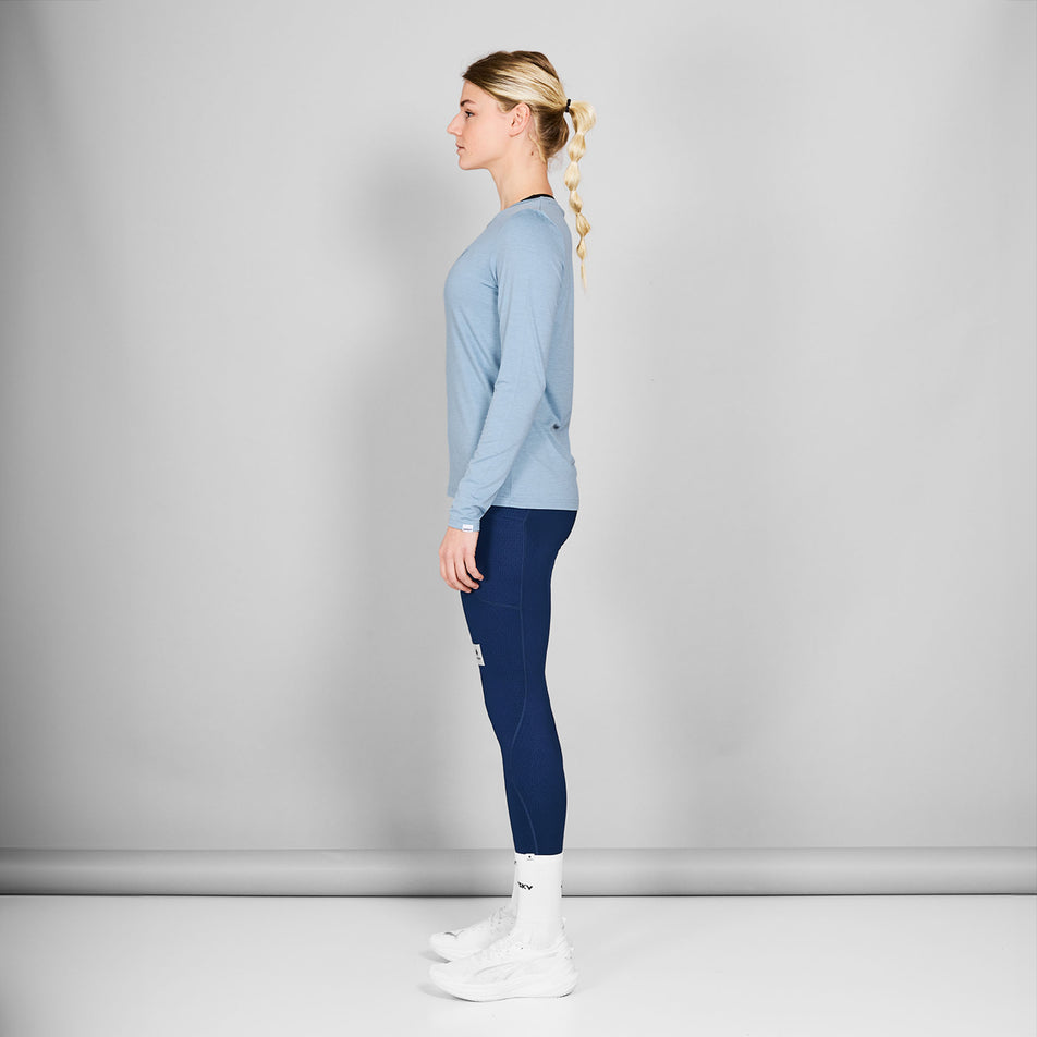 Side view of a model wearing the SAYSKY Women's Logo Pace Long Sleeve in the Blue Melange colourway. Model is also wearing tights, socks and shoes. (8602010452130)
