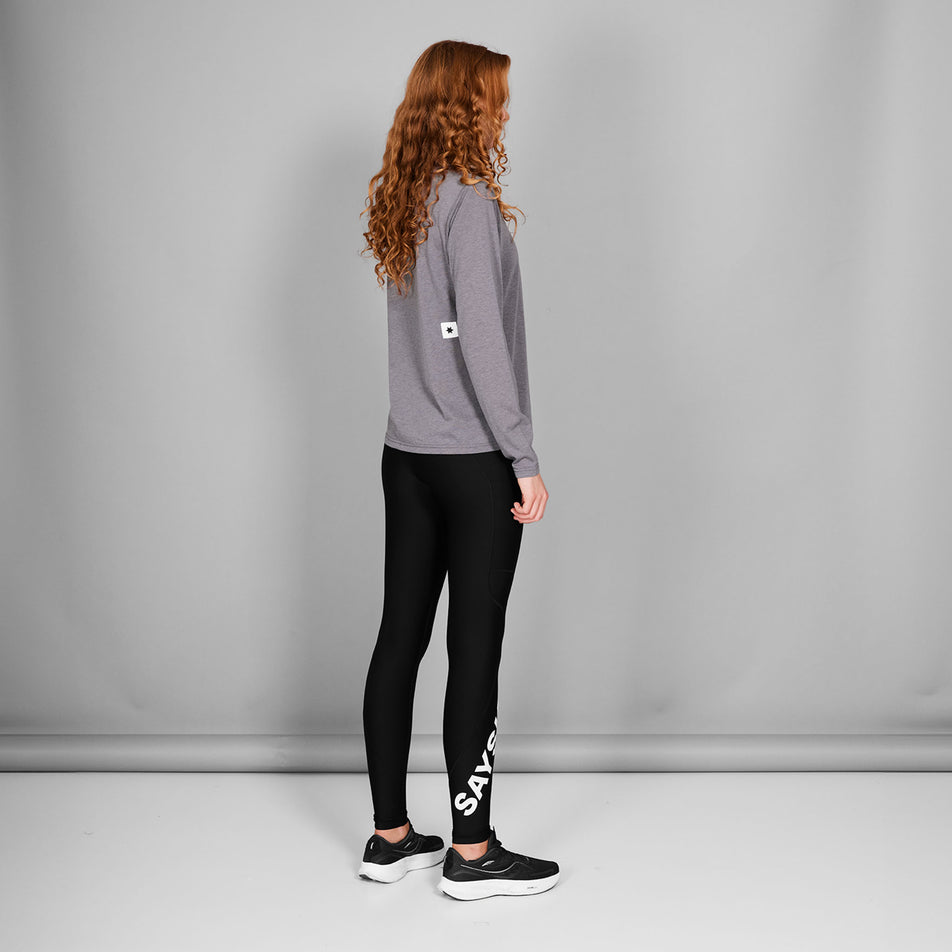 Back view of a model wearing the SAYSKY Women's Logo Motion+ Long Tights in the Black colourway. Model is also wearing shoes and a top. (8602027950242)