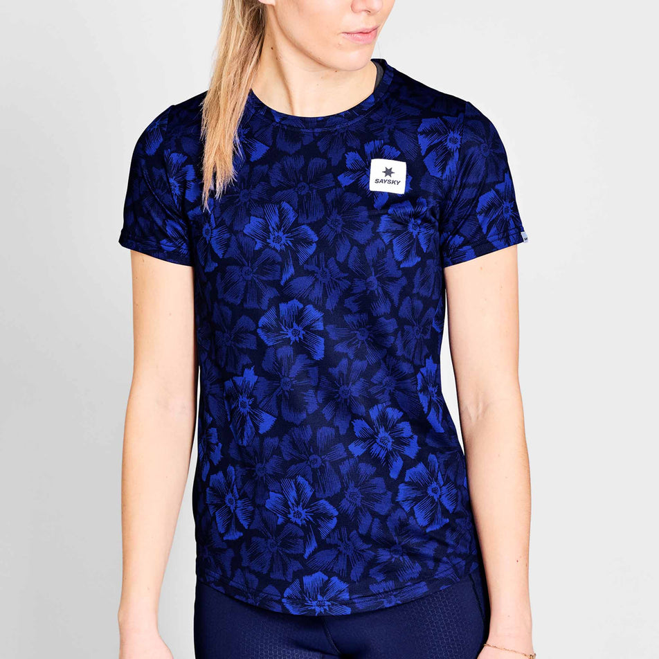 Front view of a model wearing a SAYSKY Women's Flower Combat T-Shirt in the Blue AOP colourway. Model is also wearing legwear. (8663044915362)