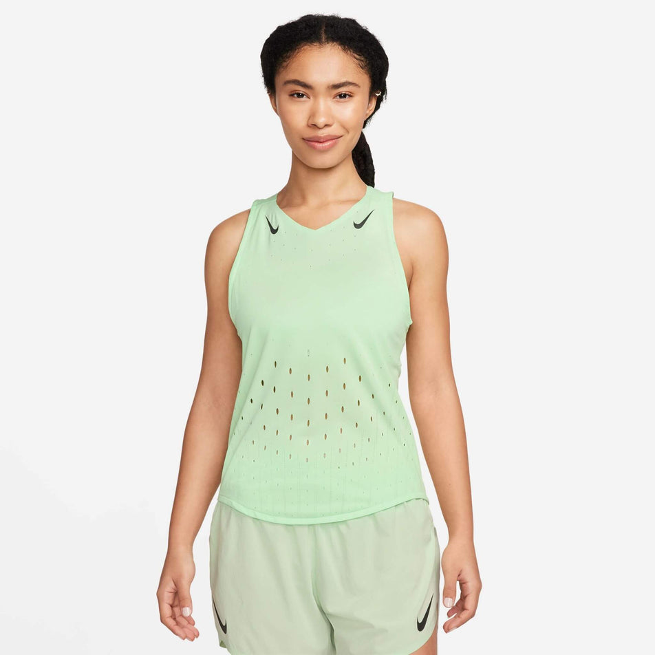 Front view of a model wearing the Women's AeroSwift Dri-FIT ADV Running Singlet in the Vapor Green/Black colourway. Model is also wearing Nike shorts. (8186003357858)