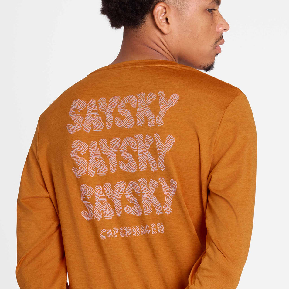 Back view of a model wearing the SAYSKY Men's Reflective Logo Pace Long Sleeve in the Orange colourway. (8788197605538)