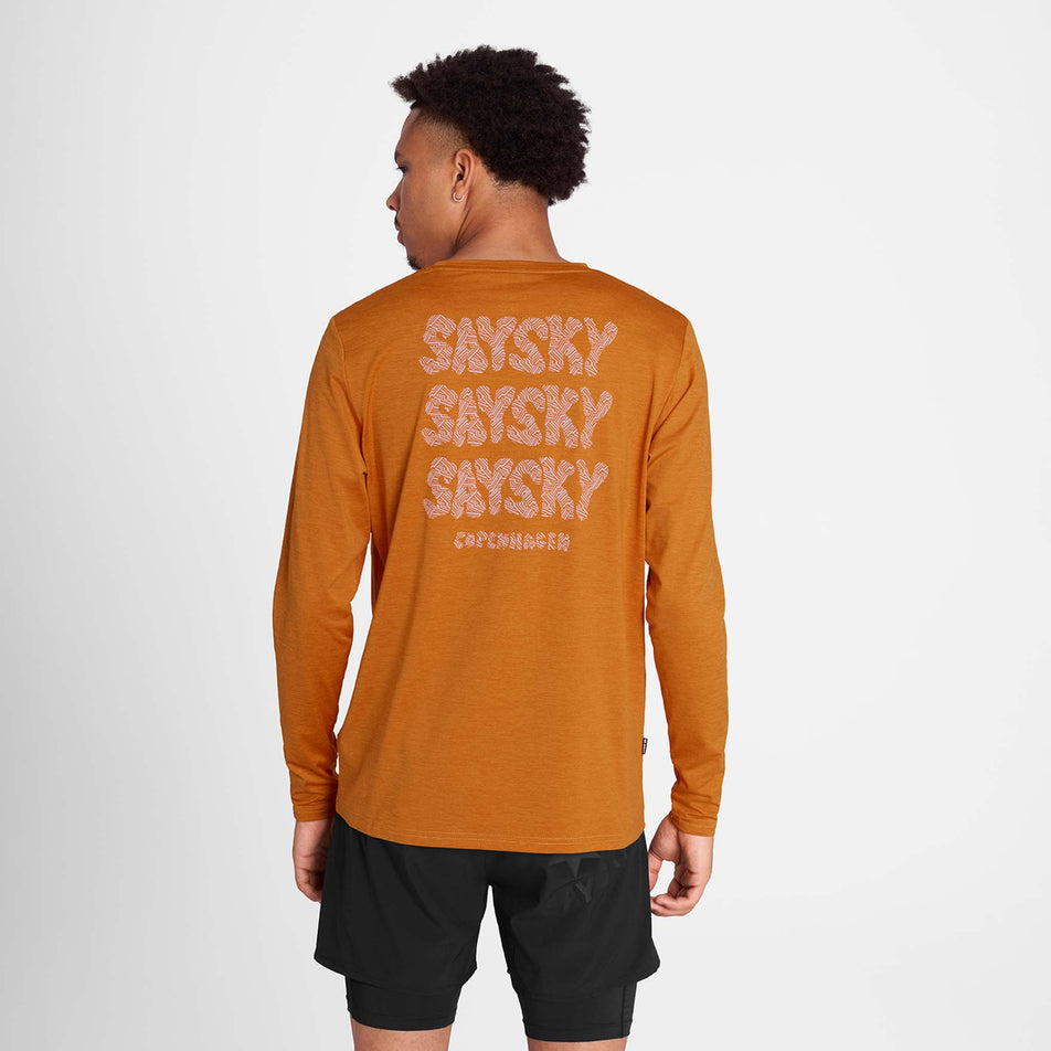 Back view of a model wearing the SAYSKY Men's Reflective Logo Pace Long Sleeve in the Orange colourway. (8788197605538)