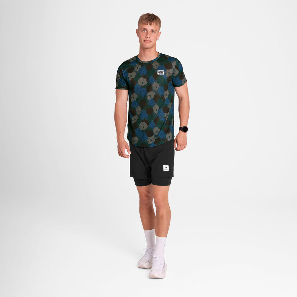 Front view of a model wearing the SAYSKY Men's Flower Combat T-Shirt in the Blue AOP colourway. Model is also wearing shorts, socks and shoes. (8756181434530)