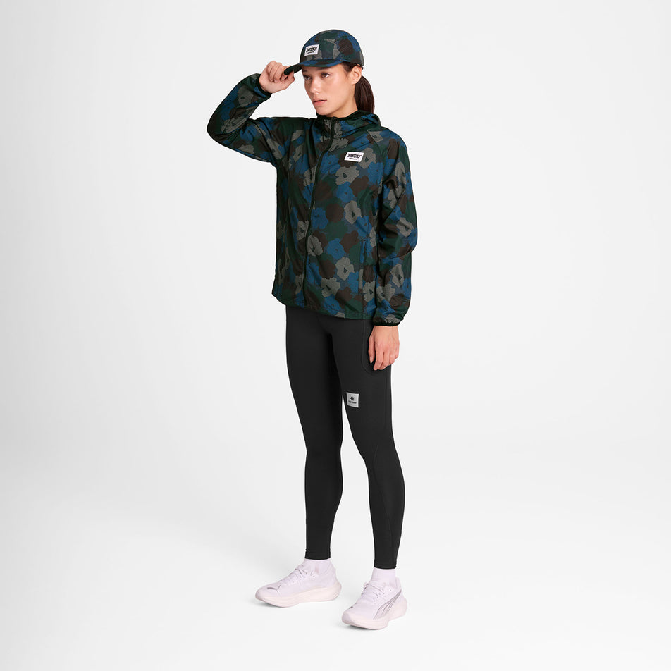Front view of a model wearing the SAYSKY Women's Flower Pace Jacket in the Blue AOP colourway. Model is also wearing leggings, socks, shoes, and a cap. (8756501971106)