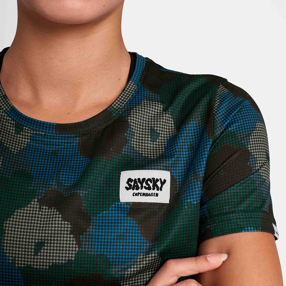 Close-up of the SAYSKY logo on a SAYSKY Women's Flower Combat T-Shirt in the Blue AOP colourway. Top is being worn by a model. (8756513570978)