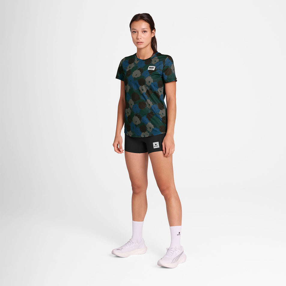 Front view of a model wearing the SAYSKY Women's Flower Combat T-Shirt in the Blue AOP colourway. Model is also wearing short tights, socks and shoes. (8756513570978)