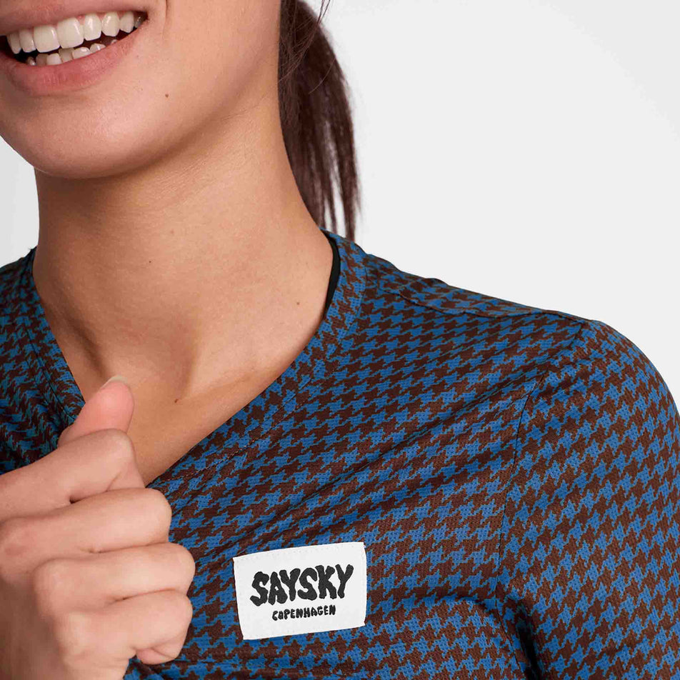Close-up of the SAYSKY logo on a SAYSKY Women's Houndstooth Combat T-Shirt in the Blue AOP colourway. Top is being worn by a model. (8756514783394)