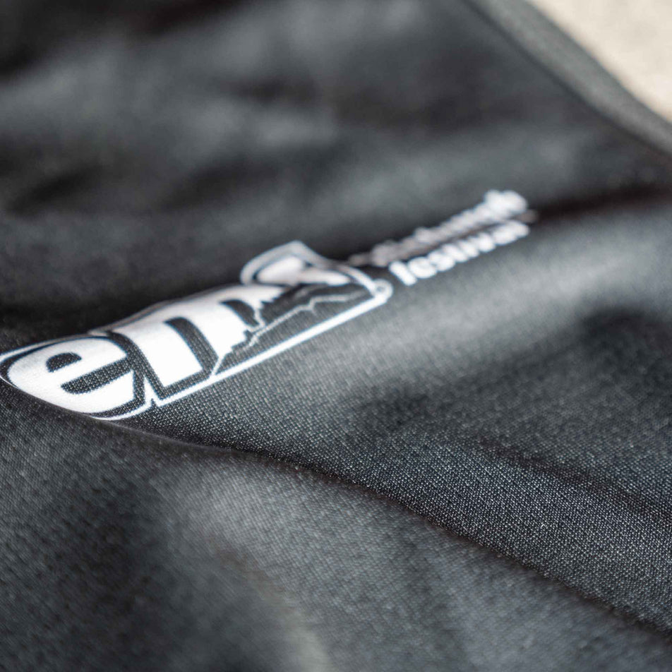 Close-up of the EMF logo on the front of a Pressio Men's Prevail S/S Top from the range of EMF Official Licensed Merchandise (8668924772514)
