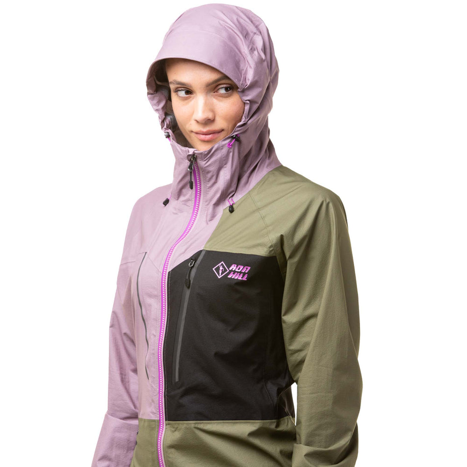 Front view of a model wearing a Ronhill Women's Tech Fortify Jacket in the Woodland/Stardust/Black colourway, with the hood up.  (8024348328098)