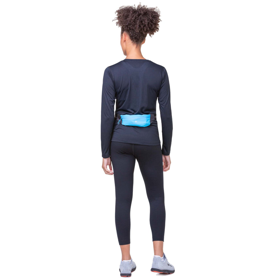 A model wearing a Ronhill Unisex Solo Waist Belt in the Cyan/Black colourway. Model is also wearing a long sleeve top, leggings and Altra running shoes. (8160945340578)