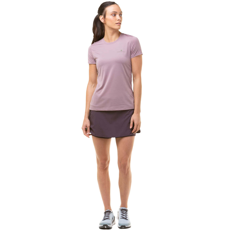 Front view of a model wearing a Ronhill Women's Tech S/S Tee in the Stardust/Woodland colourway. Model also wearing a Ronhill running skort and Altra running shoes. (8047373811874)