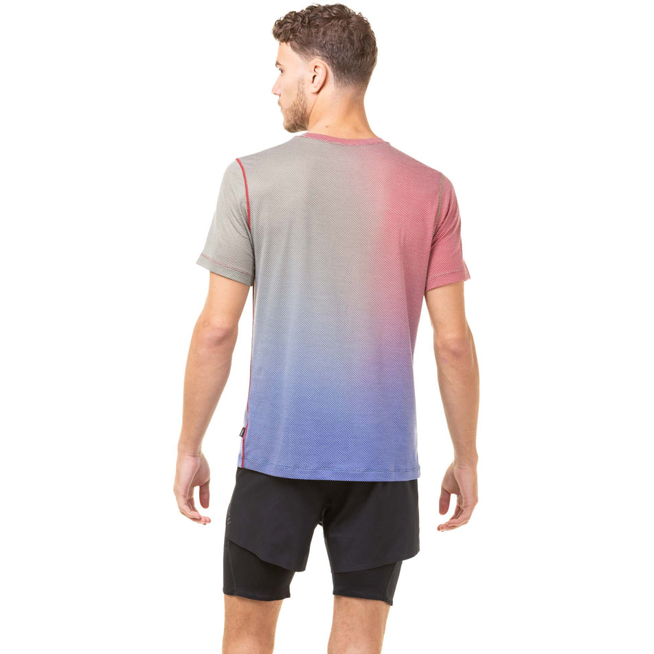 Back view of a model wearing a Ronhill Men's Tech Golden Hour Tee in the Jam/Deep Lagoon Merge colourway. Model also wearing black Ronhill running shorts. (8032265142434)
