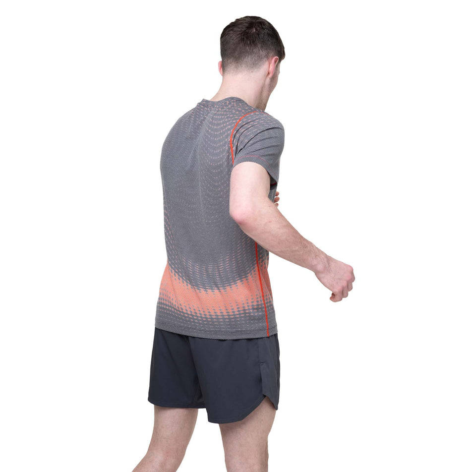 Back view of a model wearing the Ronhill Men's Tech Golden Hour S/S Tee in the Ronhill Red Motion colourway.