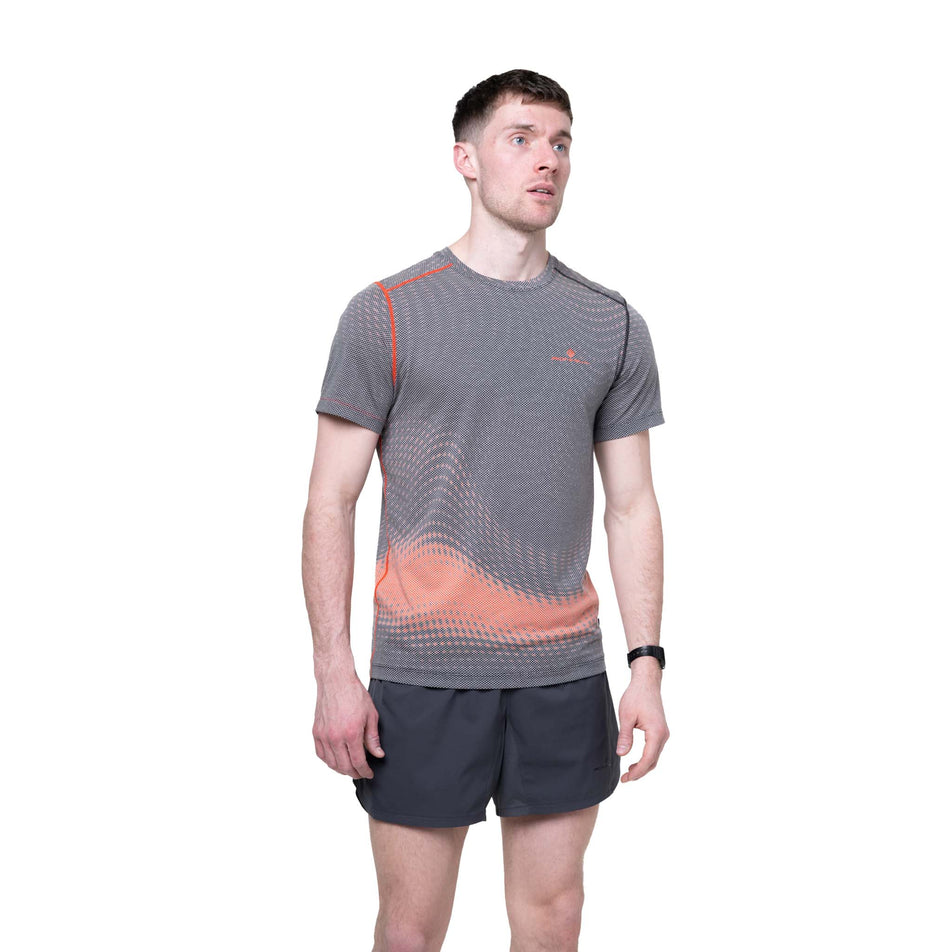 Front view of a model wearing the Ronhill Men's Tech Golden Hour S/S Tee in the Ronhill Red Motion colourway.