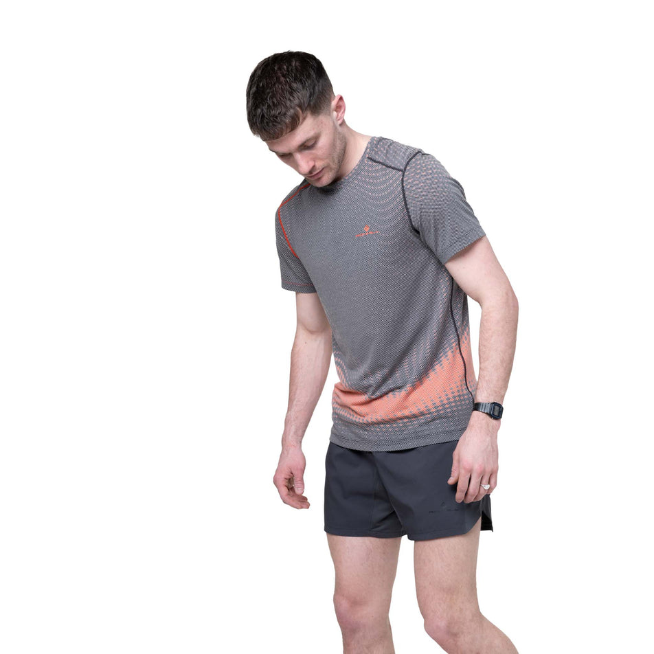 Front view of a model wearing the Ronhill Men's Tech Golden Hour S/S Tee in the Ronhill Red Motion colourway.