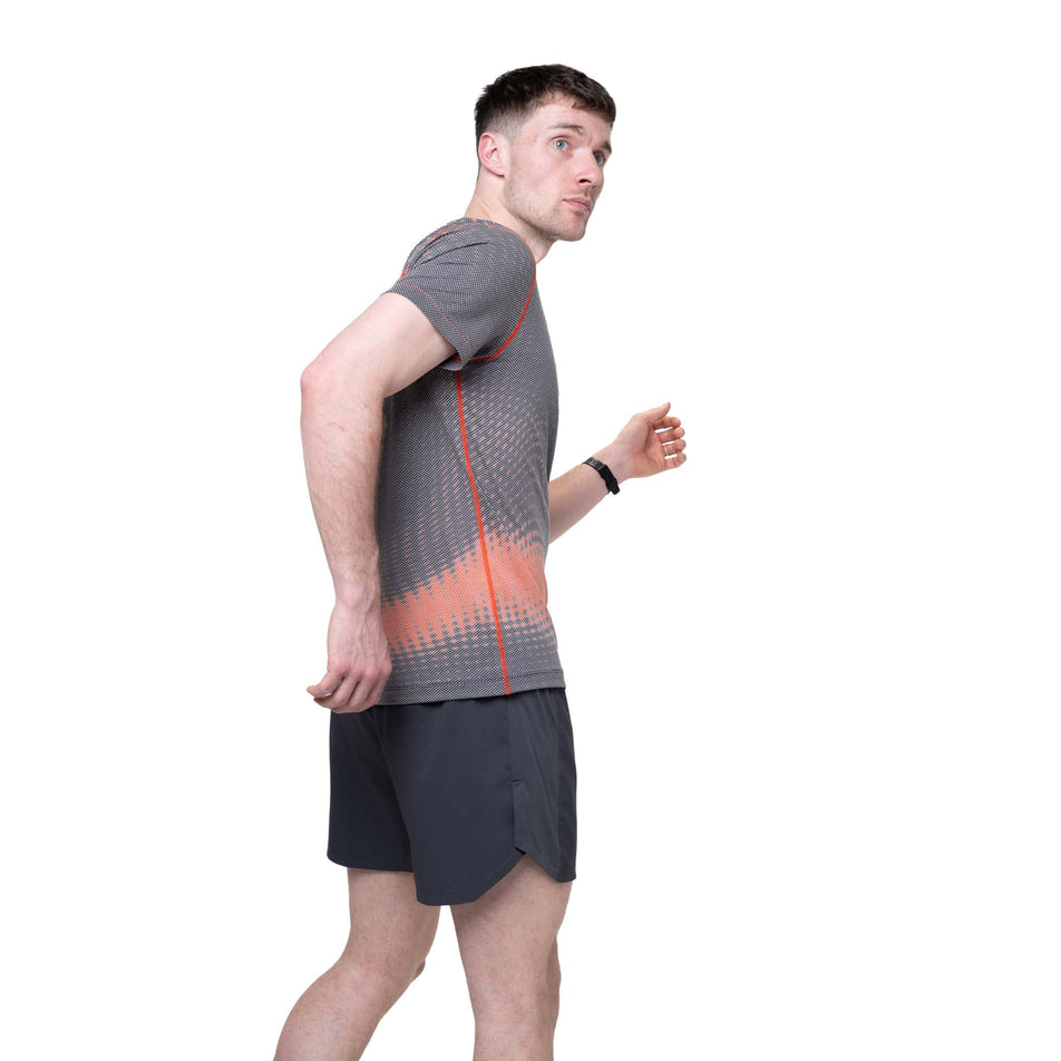 Side view of a model wearing the Ronhill Men's Tech Golden Hour S/S Tee in the Ronhill Red Motion colourway.