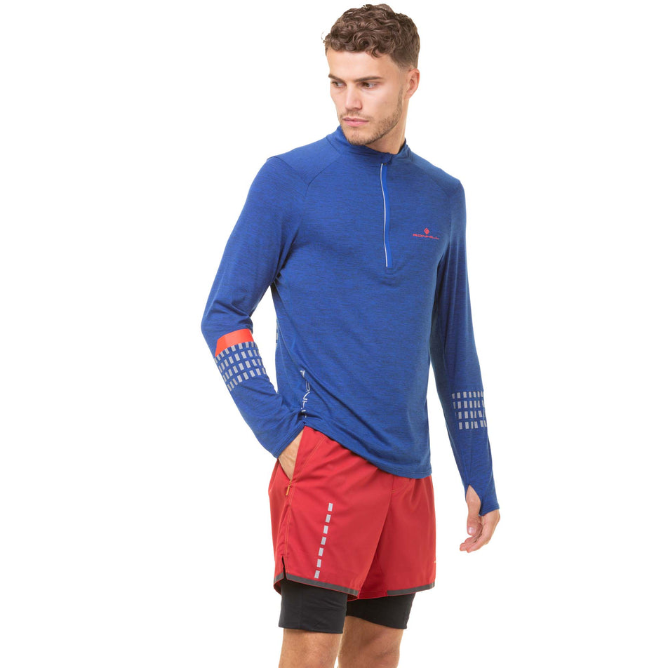 Front view of a model wearing a Ronhill Men's Tech Afterhours 1/2 Zip Tee in the Cobalt Marl/Flame/Reflect colourway. Model also wearing red Ronhill shorts.  (8032204390562)