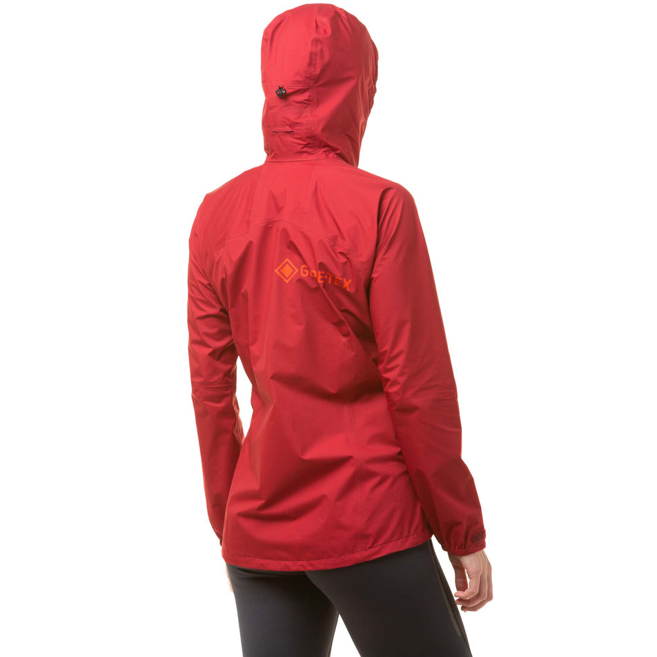 Back view of a model wearing a Ronhill Women's Tech GORE-TEX Mercurial Jacket in the Jame/Flame colourway. Jacket is being worn with the hood up. (8047328034978)