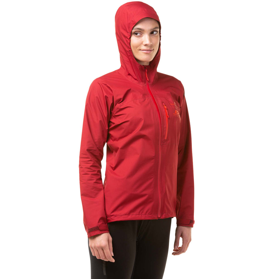 Front view of a model wearing a Ronhill Women's Tech GORE-TEX Mercurial Jacket in the Jame/Flame colourway. Jacket is being worn with the hood up. (8047328034978)