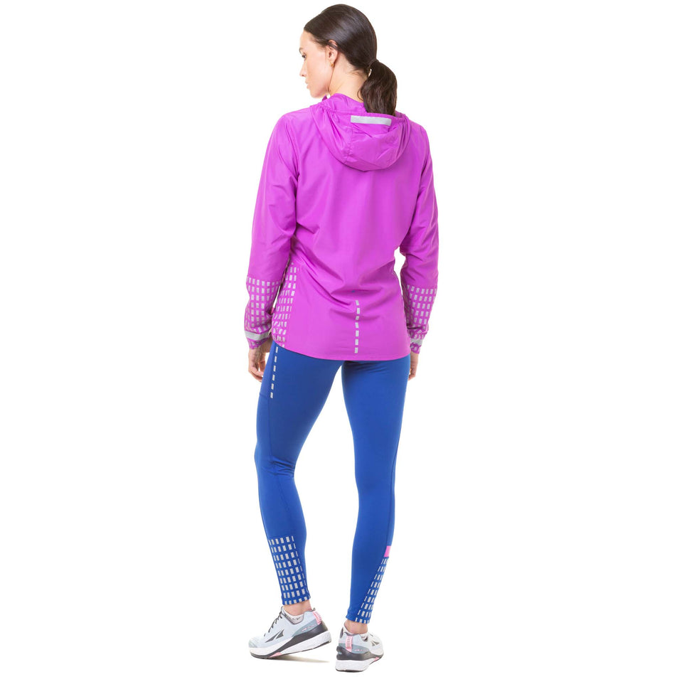 Back view of model wearing a Ronhill Women's Tech Afterhours Jacket in the Thistle/Cobalt/Reflect colourway. Model is also wearing blue Ronhill leggings and Altra running shoes. (8047250374818)