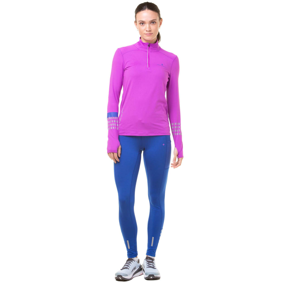 Front view of a model wearing a Ronhill Women's Tech Afterhours 1/2 Zip Tee in the Thistle/Cobalt/Reflect colourway. Model is also wearing blue Ronhill running leggings and Altra running shoes. (8047267807394)